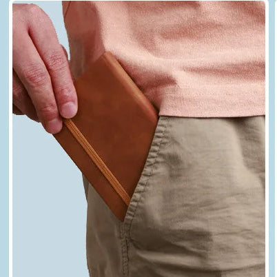 Small and portable leather notebook held by a person, with text on the cover.